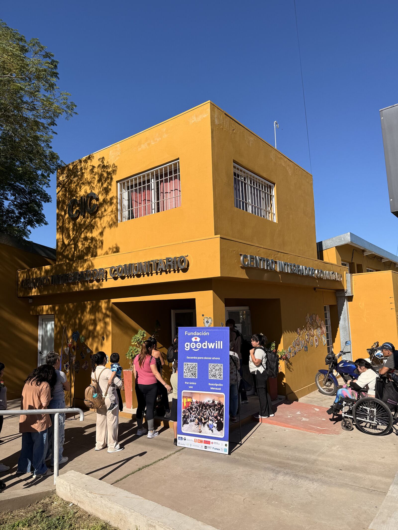 El centro integrador comunitario con el cartel de Goodwill y las familias esperando en la puerta.
