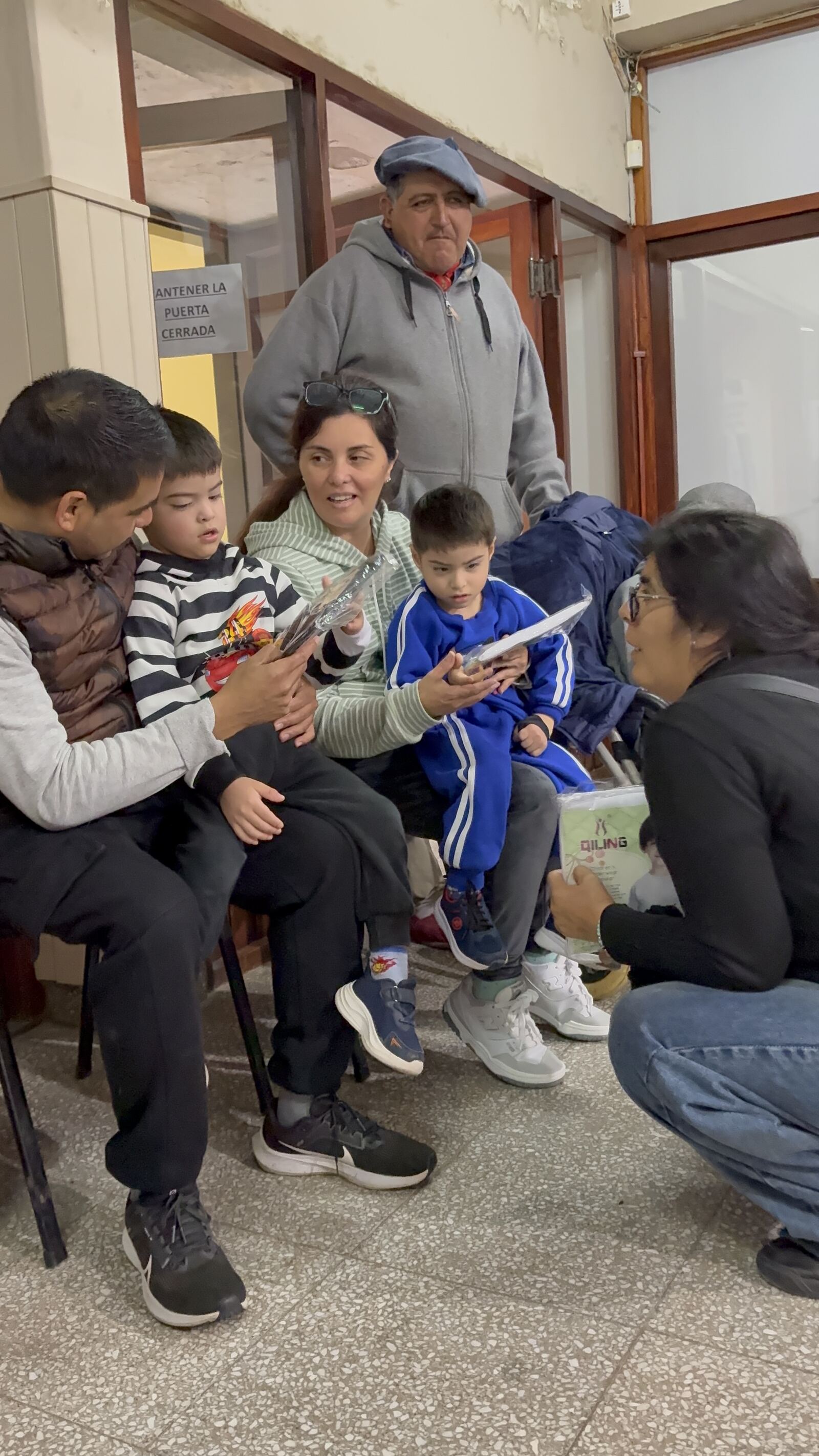 Familias esperando en el pasillo del centro, con los chicos en la falda.