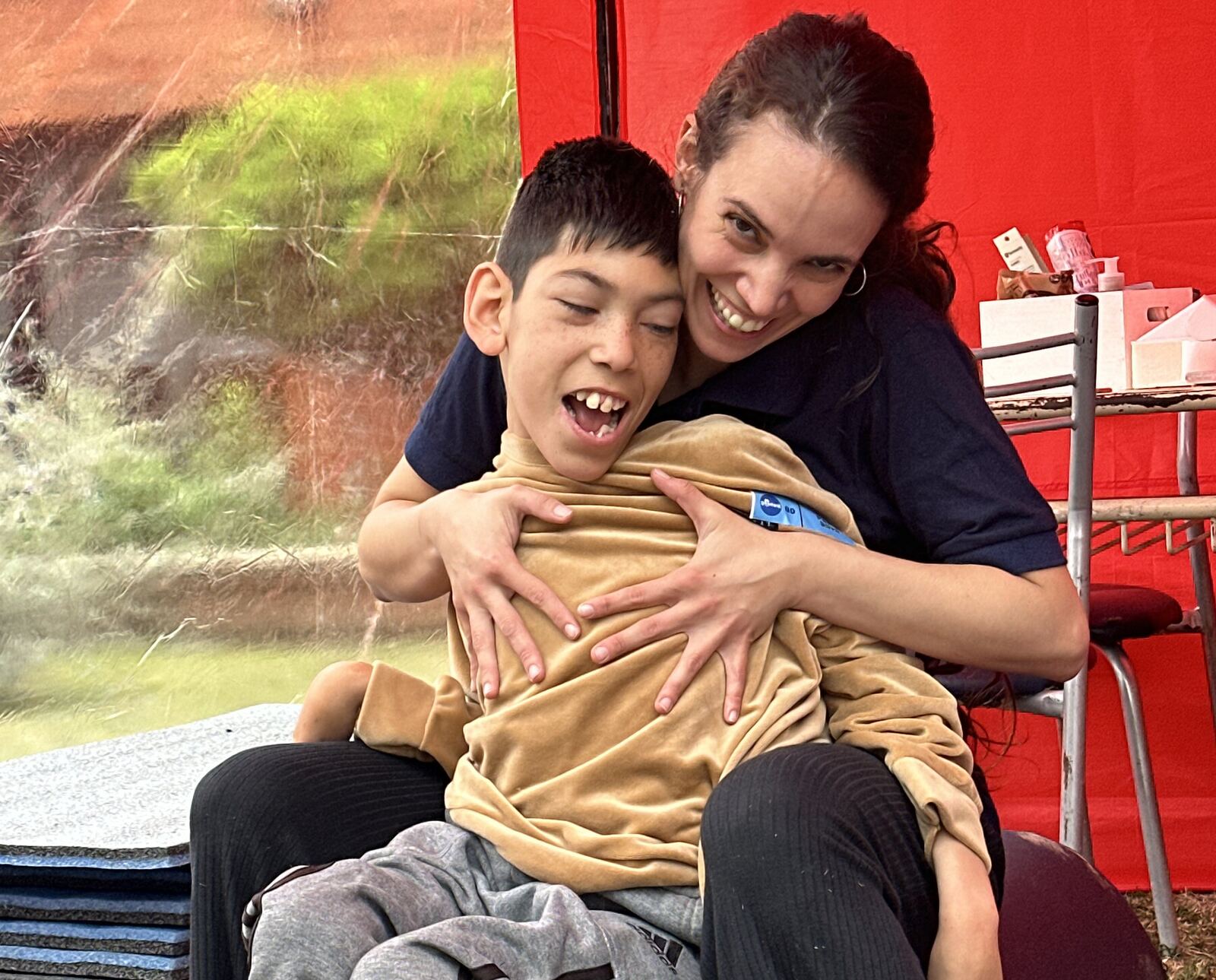 Una profesional sostiene a un nene sobre la pelota de terapia; los dos se ríen.